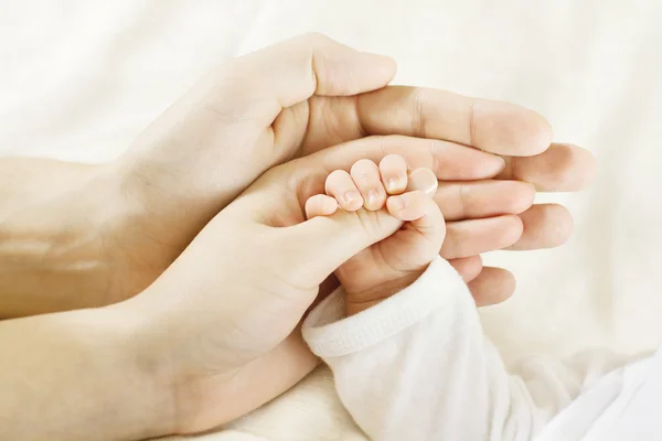 Mãos de mãe segurando os pezinhos do recém-nascido formando um coração, transmitindo amor e cuidado